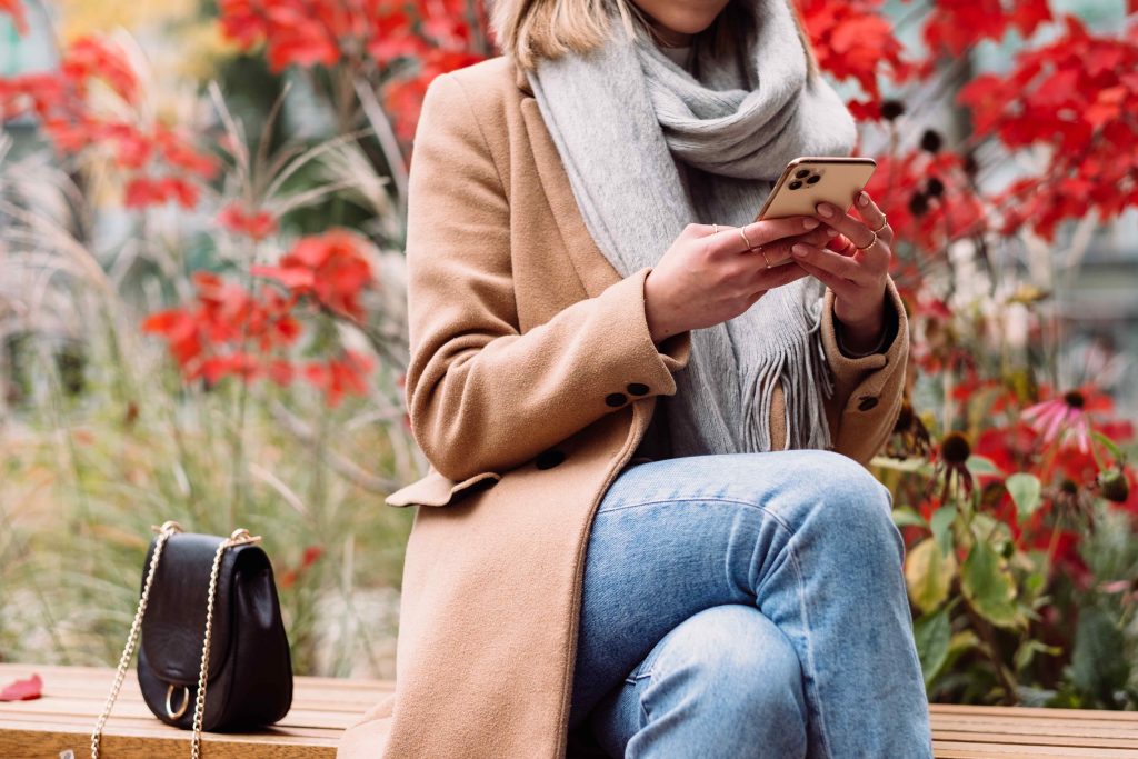 Stock photo of woman sitting on a bench using her phone